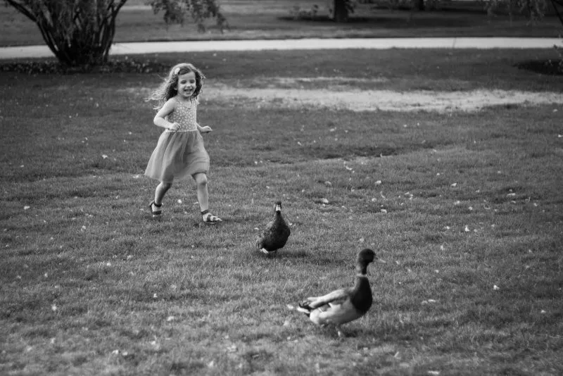 grayscale photo of girl in dress walking on grass field